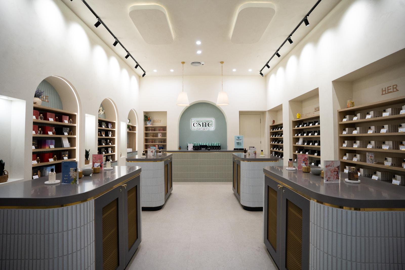 Modern perfumery shop interior with dual service counters, wall-mounted display shelving, and contemporary lighting