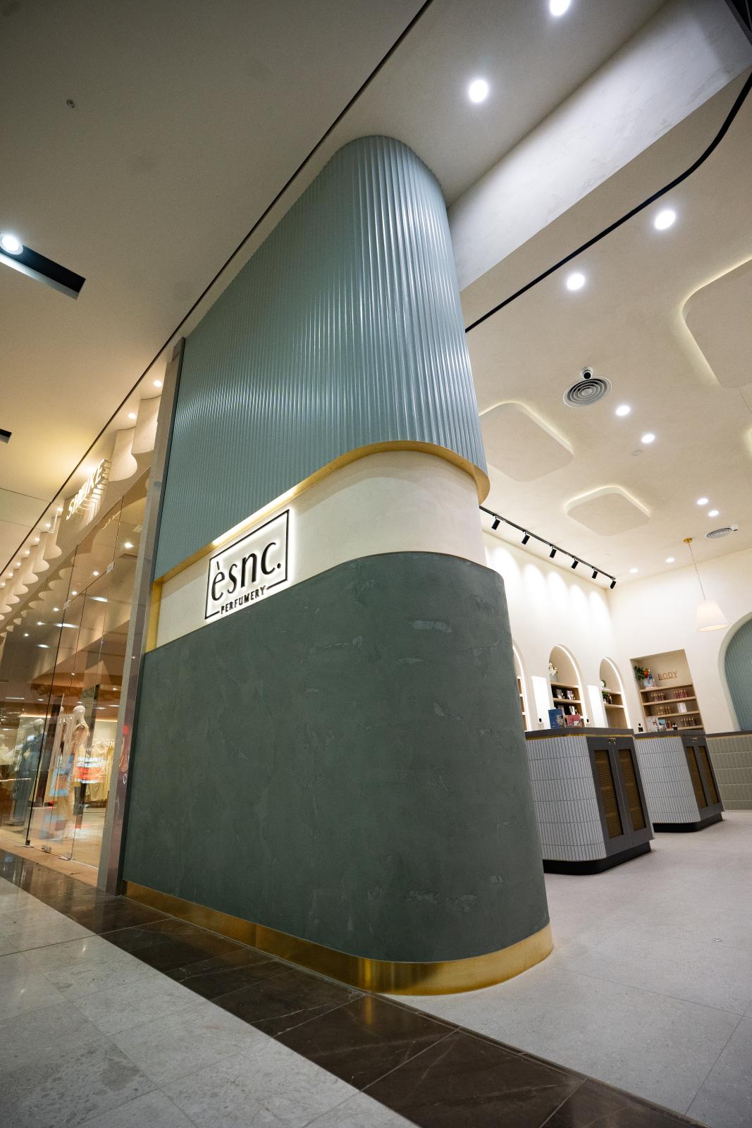 Contemporary retail storefront with curved teal feature wall and brass accents in modern shopping centre