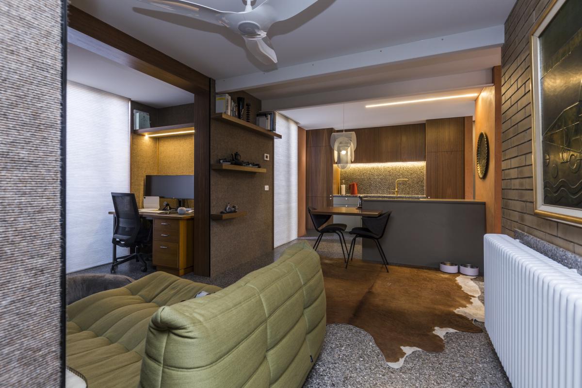 Contemporary home office renovation with sage green sofa, built-in desk, and modern lighting