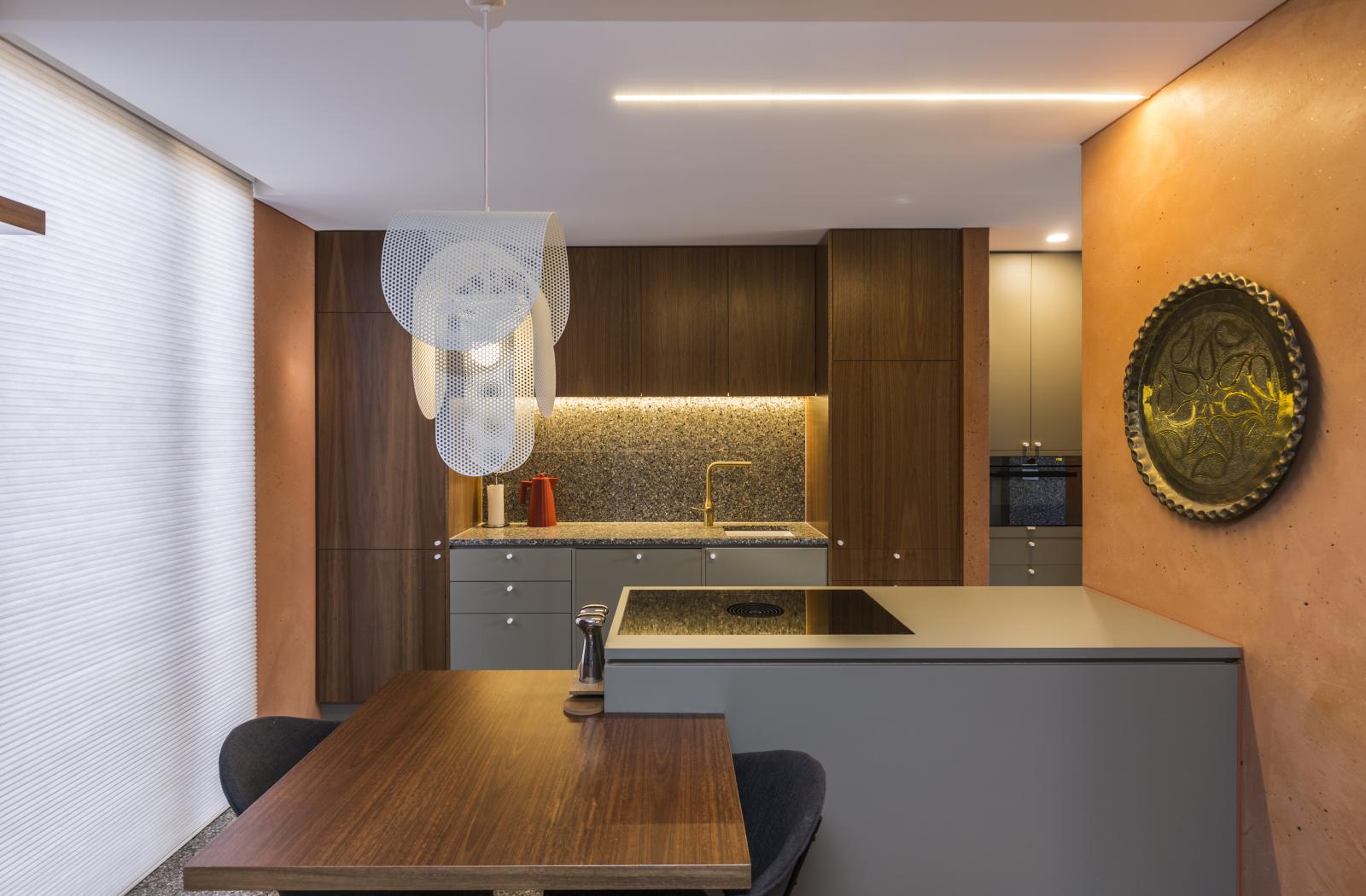 Modern commercial reception area with grey desk, wooden table, dark cabinetry, and warm ambient lighting