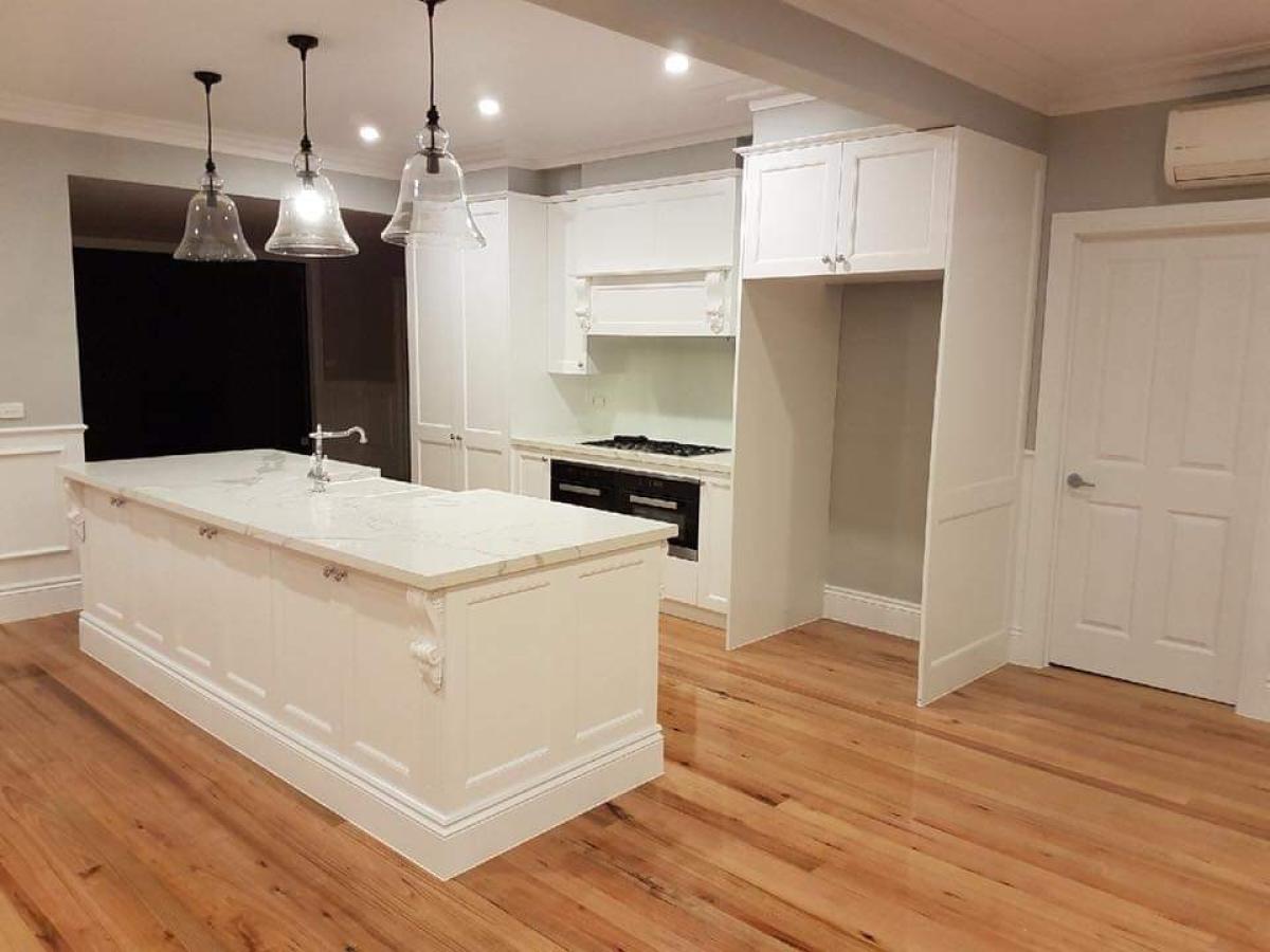 Modern white kitchen with island, pendant lights, and wooden flooring