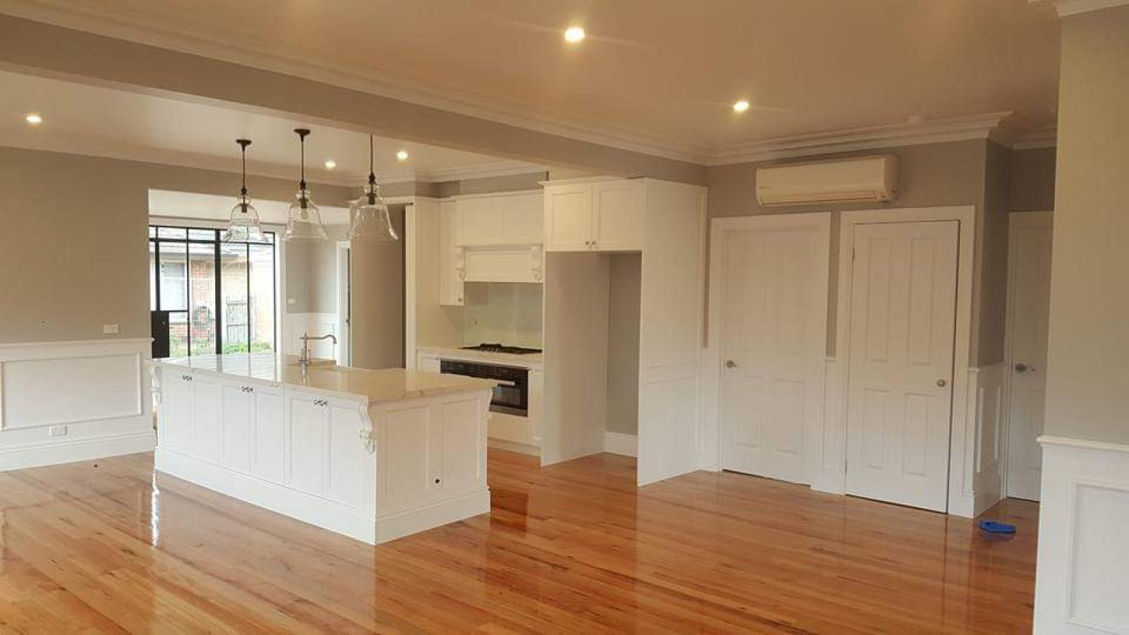 Modern kitchen renovation with white cabinetry, kitchen island, and wooden flooring