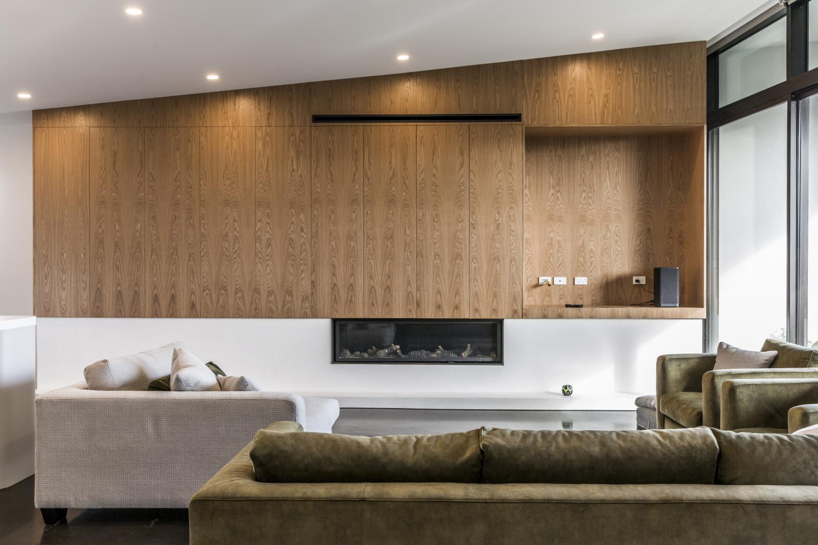 Contemporary living room with wooden feature wall, linear fireplace, and olive green seating