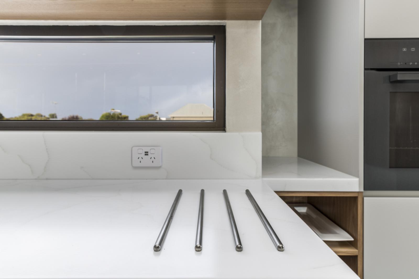 Modern kitchen with white benchtop, chrome tapware, and built-in black oven