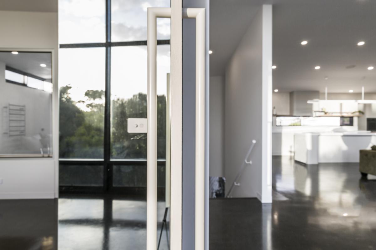 Contemporary hallway with black framed glass doors, grey walls, recessed lighting, and polished flooring