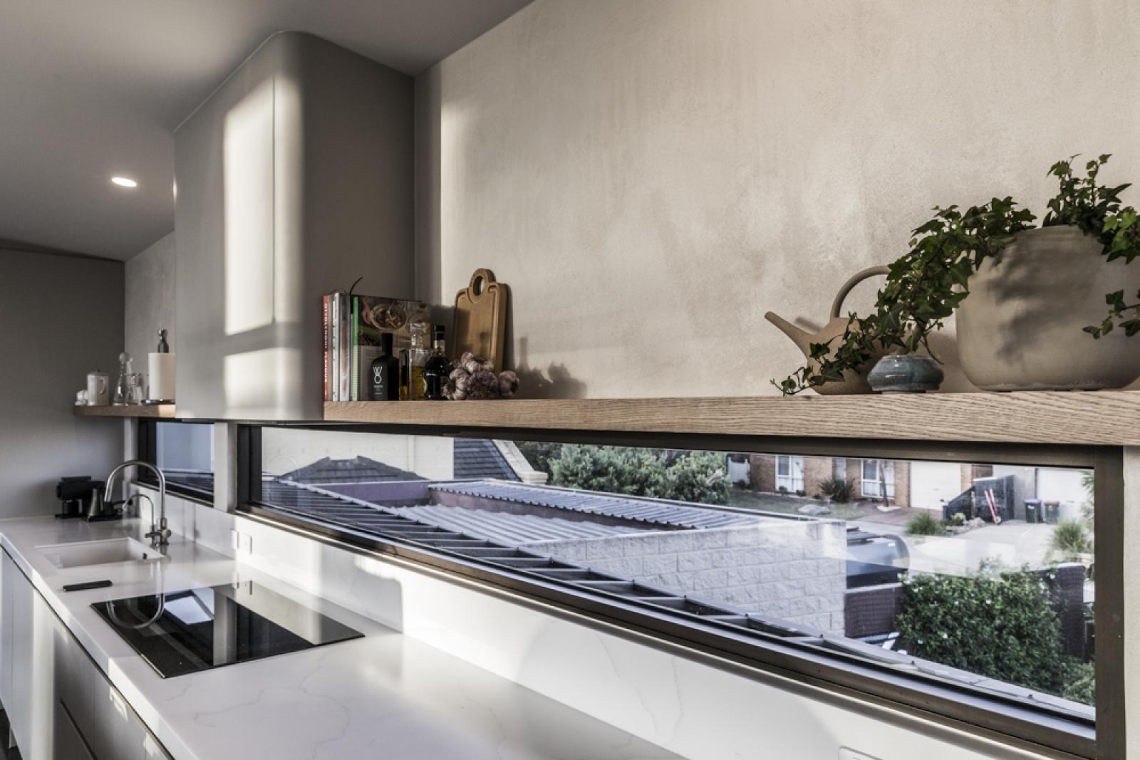 Contemporary home office with minimalist white desk, black sink, and expansive window overlooking garden
