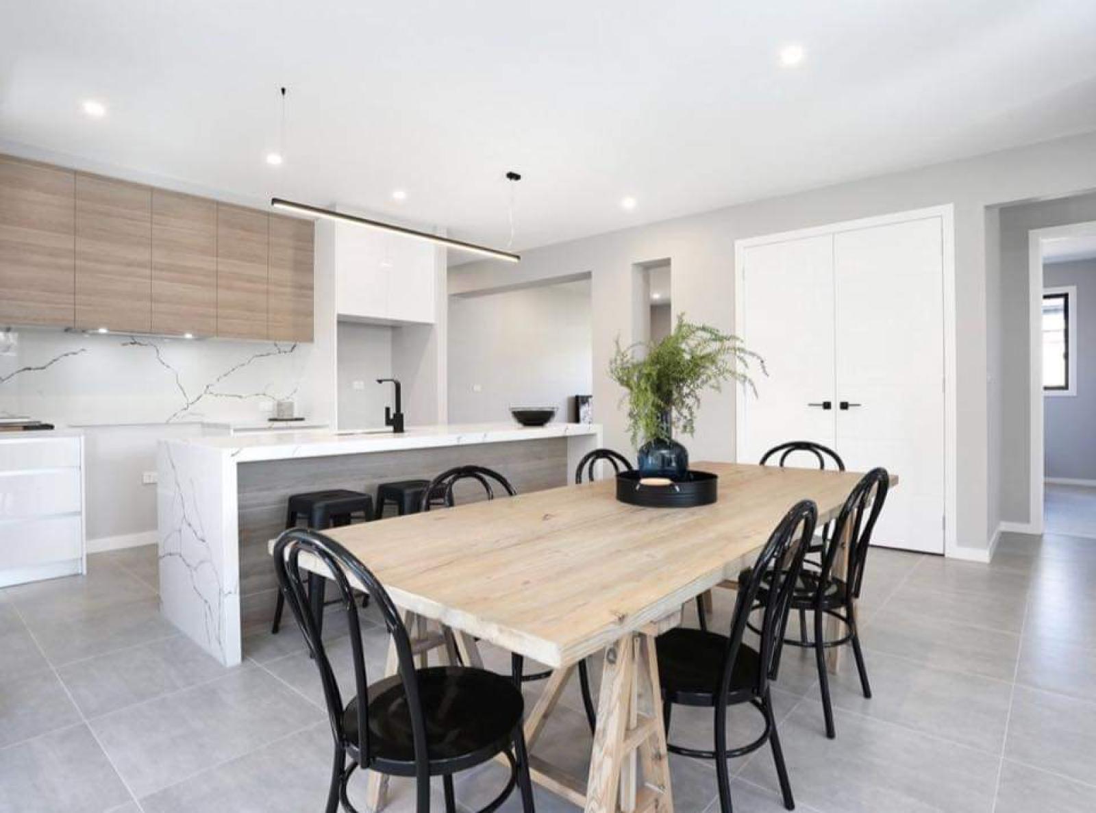 Modern kitchen and dining area with white cabinetry, timber dining table, and black chairs